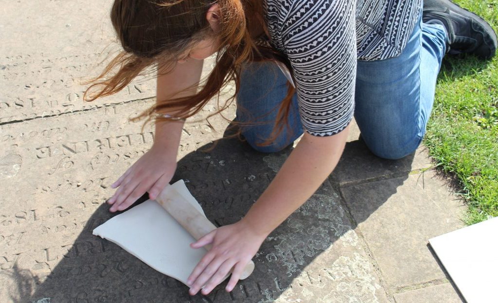 IMG_7524 an artist rolls a slab of clay over a gravestone set in the path.