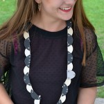 A girl is very proud of her self-made necklace with black and white semicircular discs.