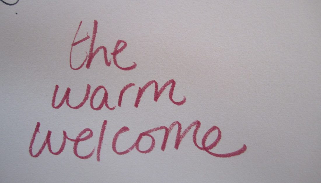 on a white sheet of paper someone wrote "the warm welcome" with a red pen