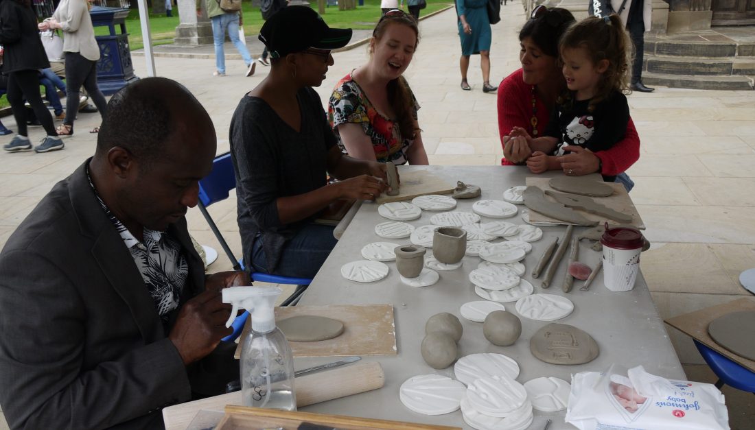 Members of the public gather around a table and play with clay.