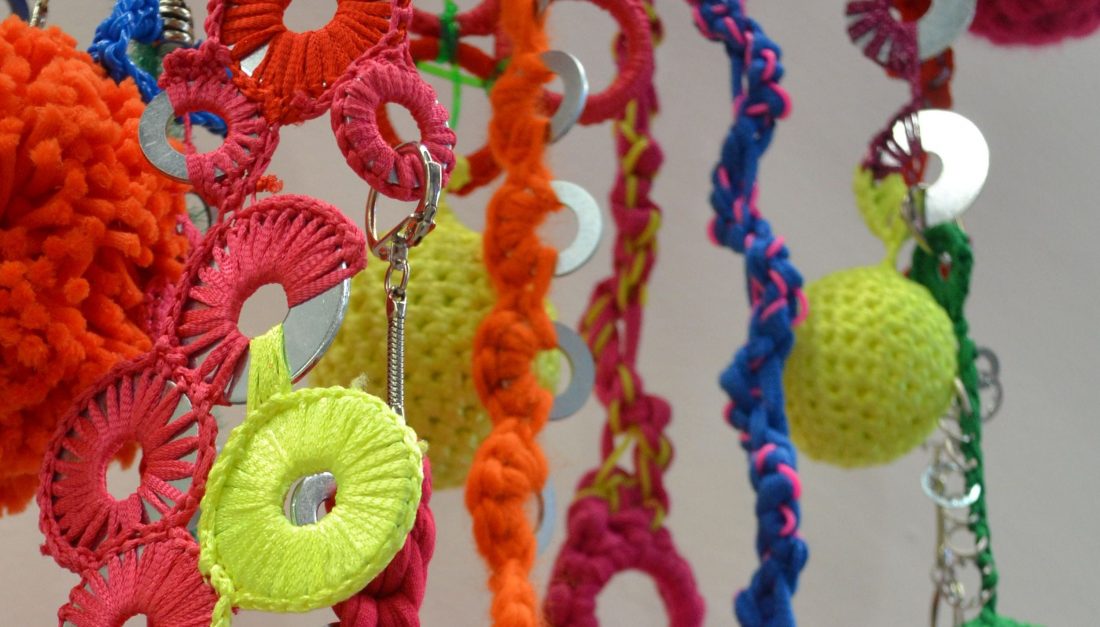 A hanging installation of colourful threads and yarns with metal washers, keyring and jumprings attached.