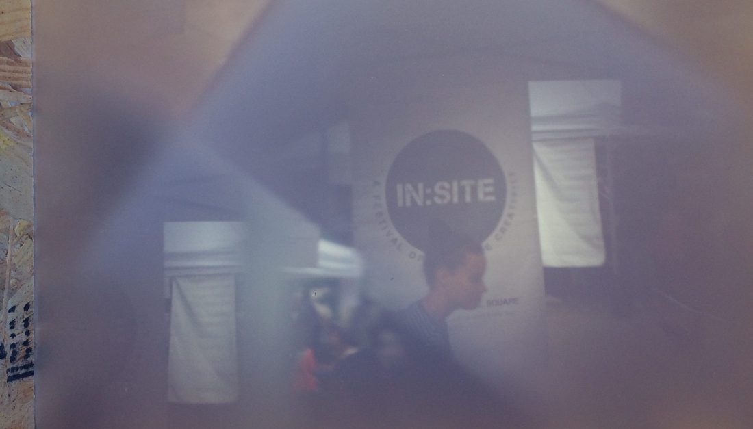 The In:Site sign on a banner with a lady walking past as seen through a camera obscura.
