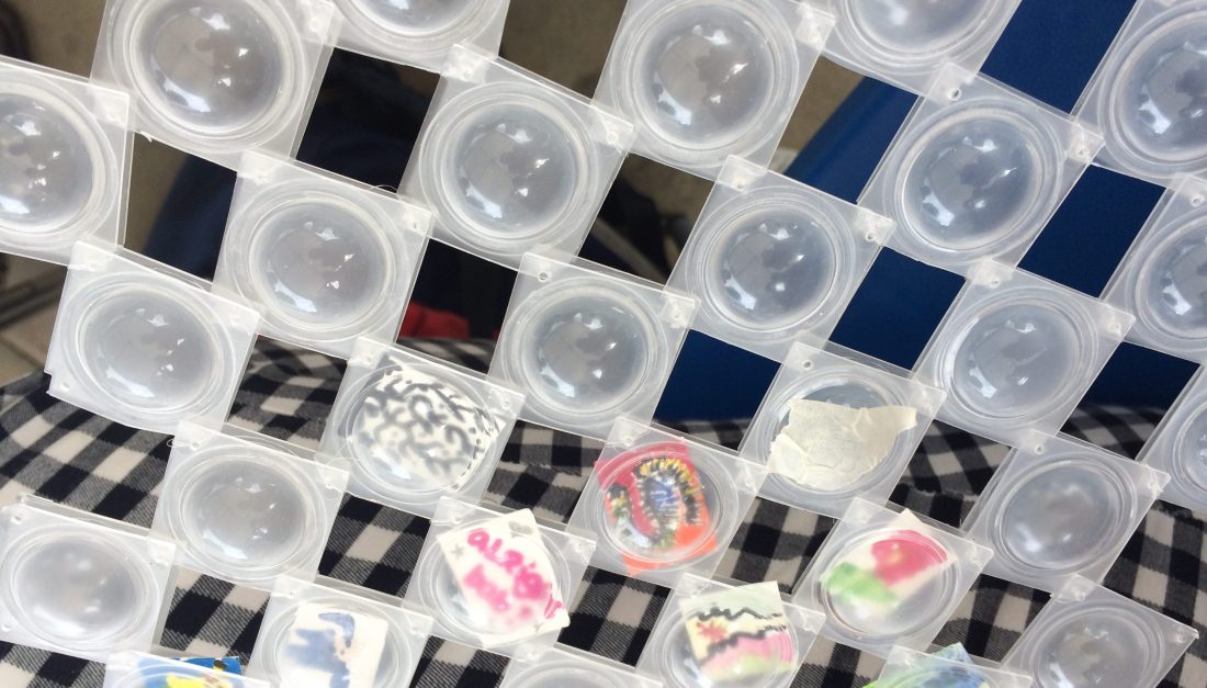 Empty used contact lens cases, some with small drawn pictures inside.