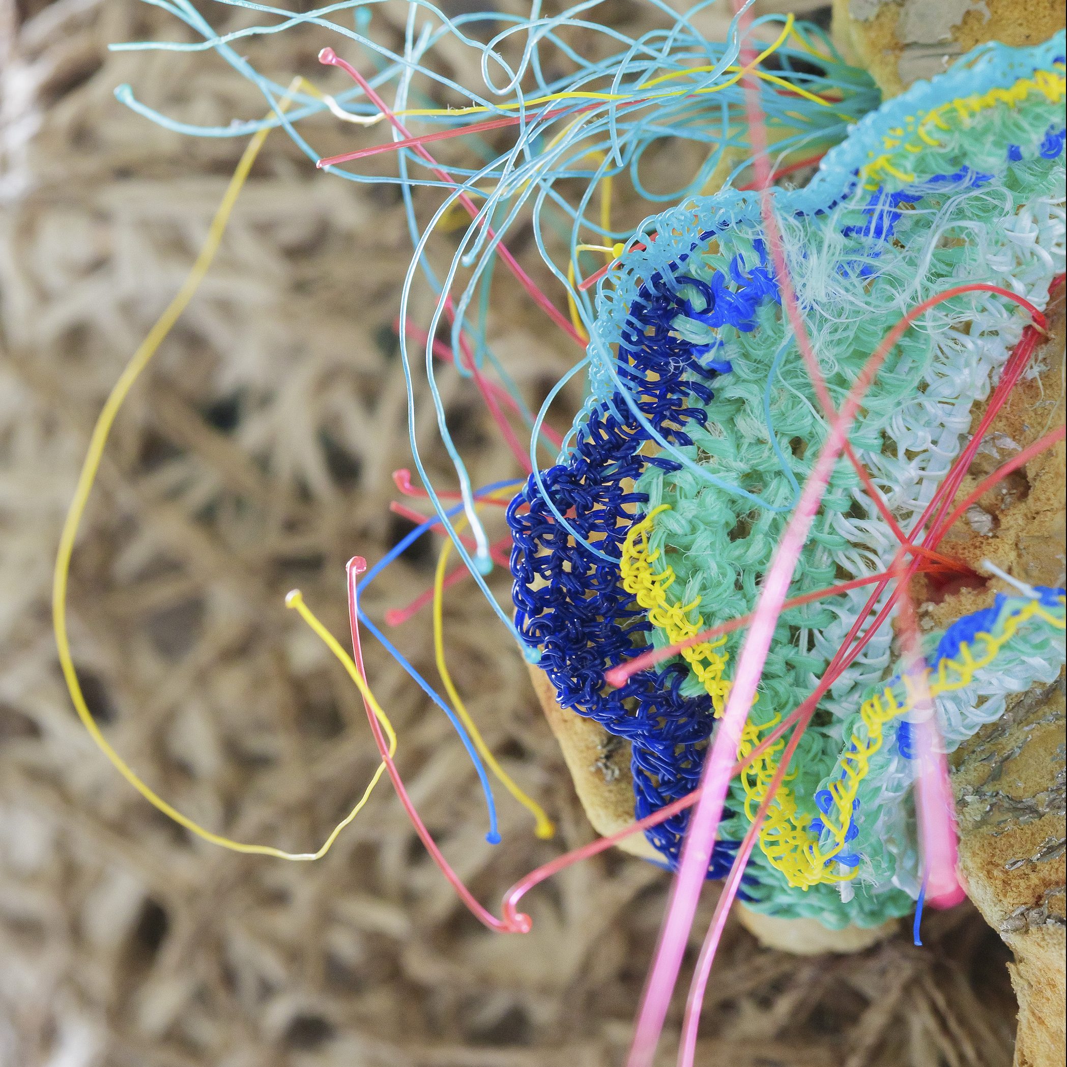 Close up shot of various colours and threads of cotton and plastic stitched together.