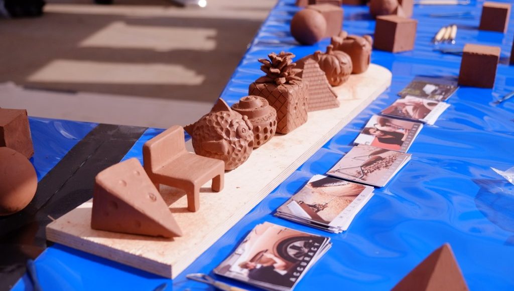 finished sculptures in many different shapes and designs are standing in one line on the table.