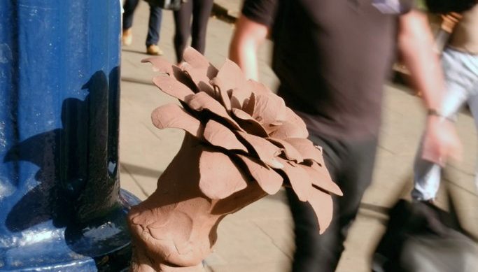 Flower sculpture is wrapped around lamp post.