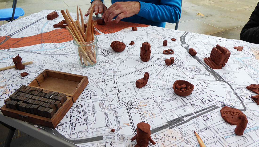 clay objects and tools on a table with Birmingham map