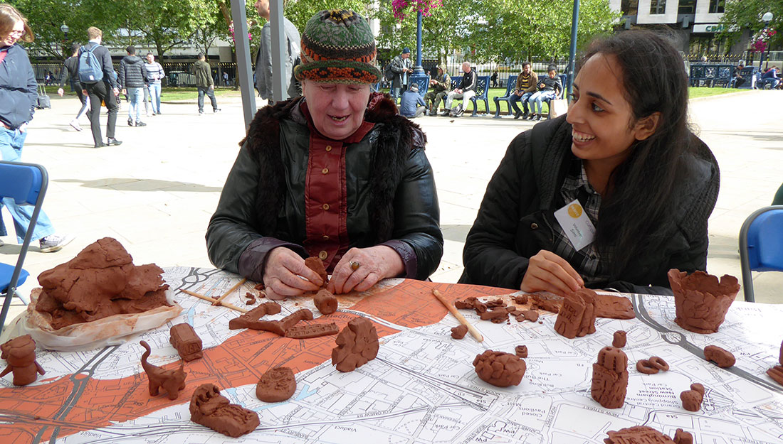 volunteer and participant making clay sculptures
