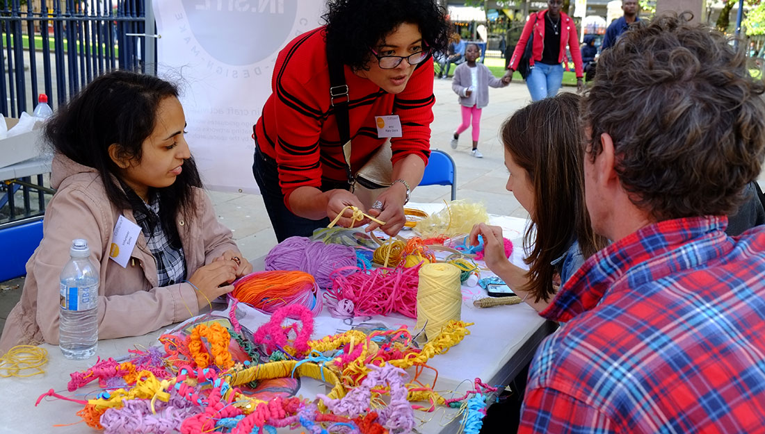 artist and volunteer showing participant different colourful yarns